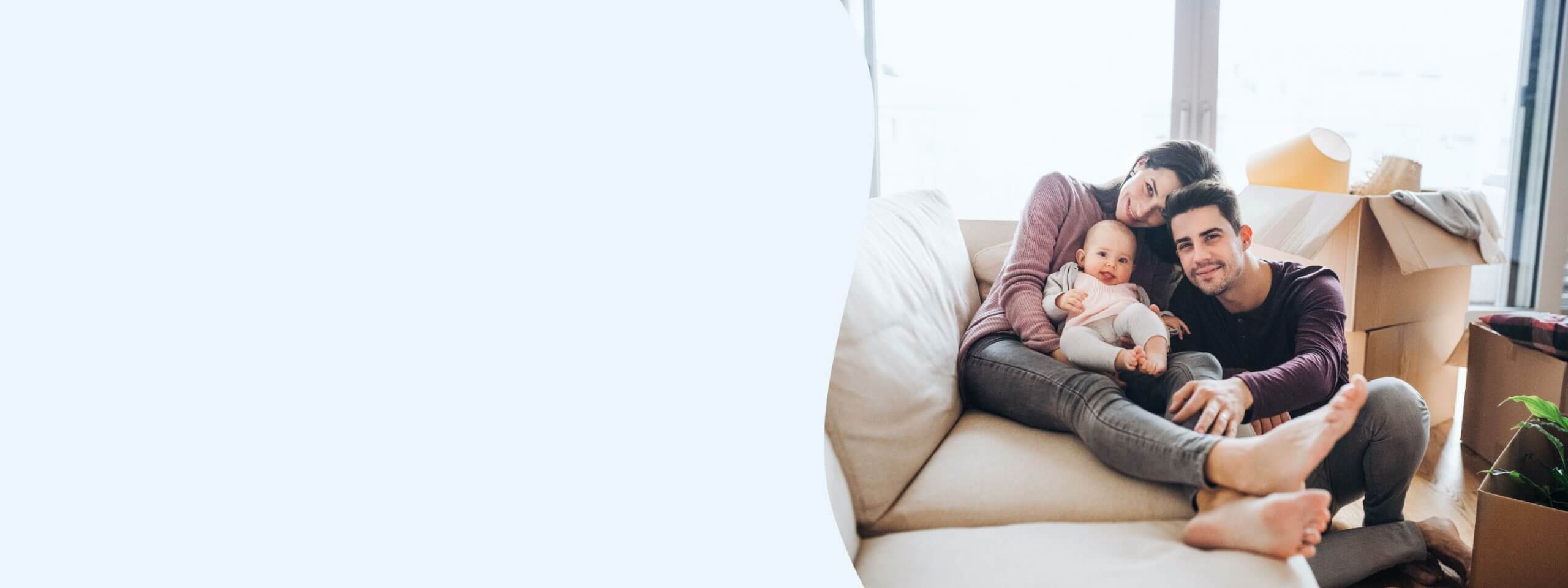 Young couple lounges with baby on couch.
